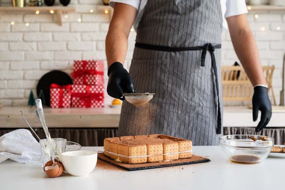 christmas-cooking-chef-cooking-dessert-in-the-kitchen-pouring-cocoa-powder-on-it-min